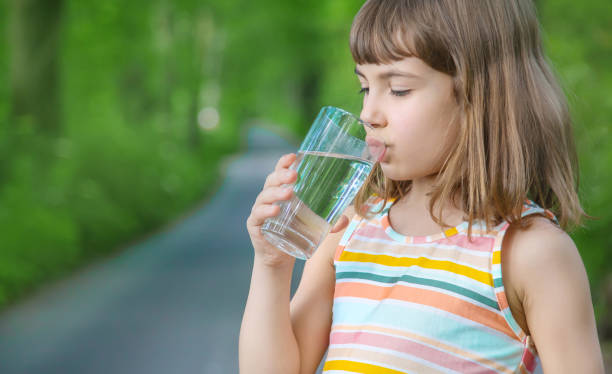 istock Cute Girl Drinking Water While Standing Outdoors 1413652028