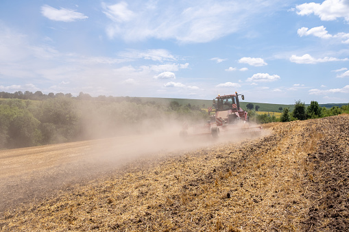 A tractor driver is plowing an agricultural field with his tractor.