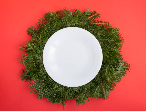 istock Top view of empty white plate on Christmas ring or wreath on the red background. Copy space. 1413652433