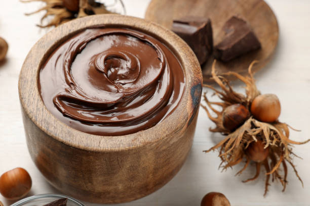 istock Bowl of tasty chocolate paste with hazelnuts on white wooden table 1413654403