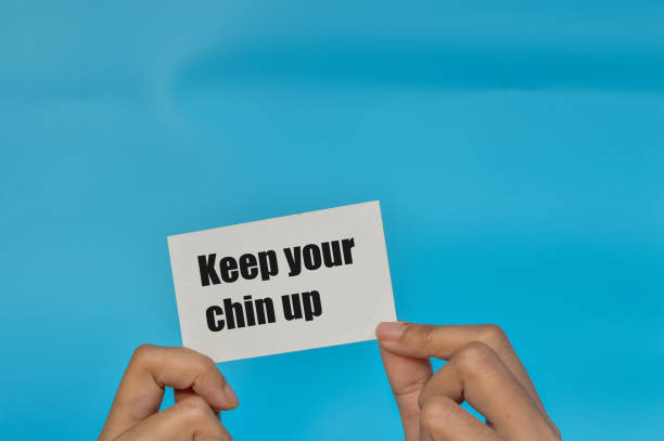 istock Hand holding white card written with phrase KEEP YOU CHIN UP 1413656374