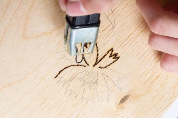 Burn out a drawing on a wooden board with an electric device with a scorcher stock photo