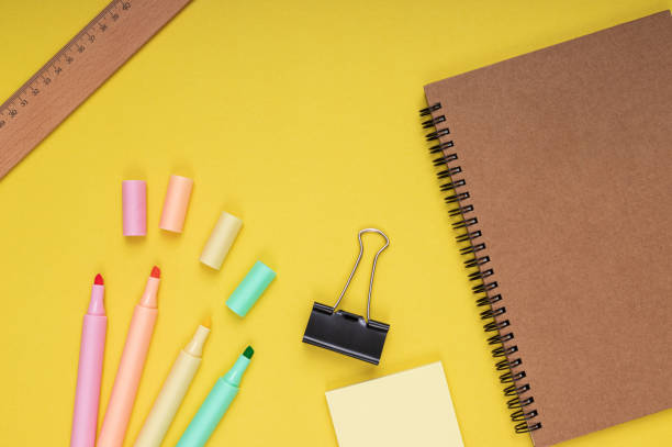 istock Notebook, colored pencils, note paper and clamp, ruler. back to school. Isolated yellow background 1413658226
