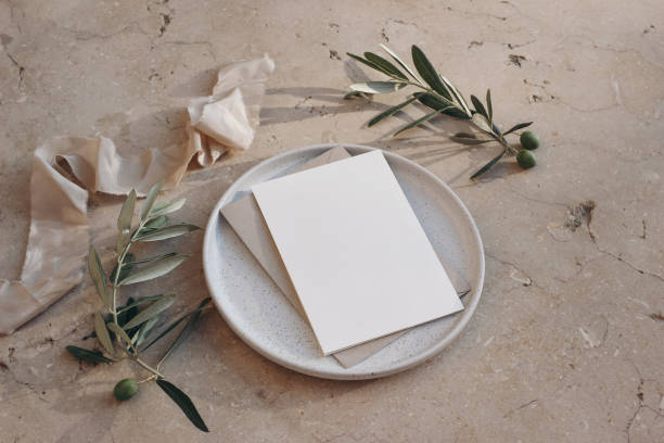 istock Mediterranean wedding stationery. Greeting card, invitation mock up. Envelope on ceramic plate. Beige marble background. Olive tree fruit, branches, silk ribbons. Summer design. Top side view. 1413660662