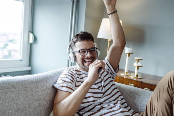 istock Emotional guy singing and using smartphone like microphone 1413662286