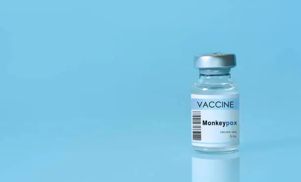 Photo of Vial with vaccine Monkeypox on a blue background.The concept of medicine, healthcare and science.Monkeypox is a viral zoonotic disease. Monkeys may harbor the virus and infect people.Copy space
