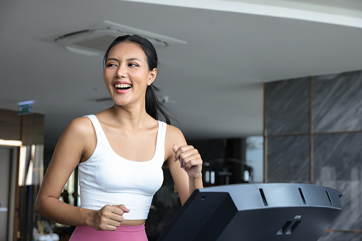 Enjoy attractive woman exercise in gym on treadmill machine, urban lifestyle after work in living condominium