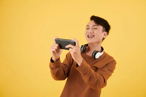 Happy excited young man playing videogame on smartphone