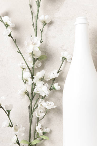 istock Flat lay white champagne bottle and flowers on a mottled light gray table top. Vertical format. 1413667459