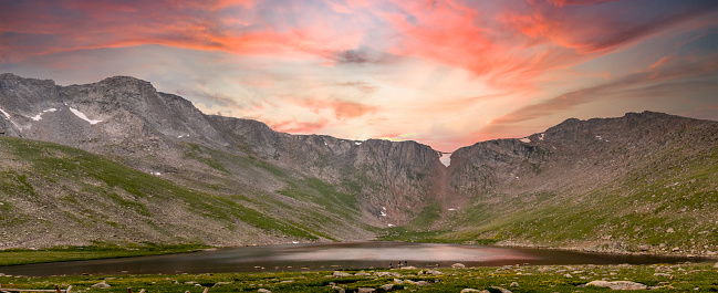 Beautiful sunset behind mountain ridge with reflection on Summit Lake near Mount Evans near Guanella pass in the Mount Evans Wilderness area. Colorado Rocky Mountains.