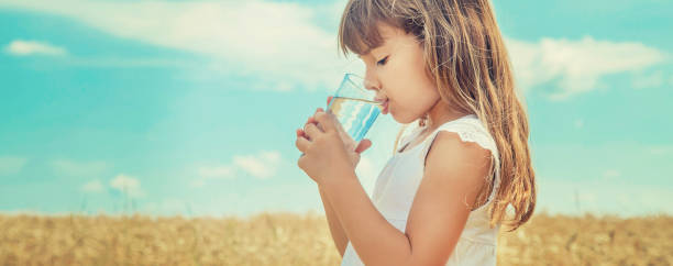 istock Young Woman Drinking Water While Standing On Field Against Sky 1413668908