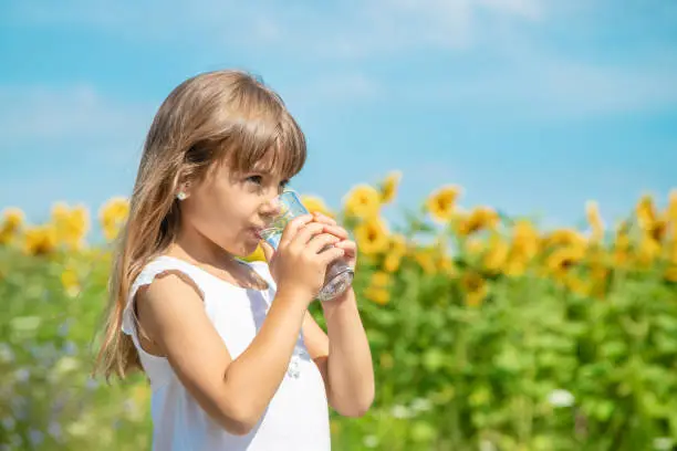 Photo of Young Woman Drinking Water While Standing Against Plants