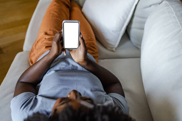 istock Young woman relaxing on the sofa and using smart phone. Device screen. 1413669658