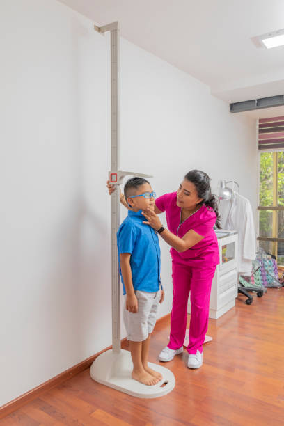 Latina pediatrician measuring a child with a wall ruler in her office Latina pediatrician measuring a child with a wall ruler in her office. boy height measure stock pictures, royalty-free photos & images