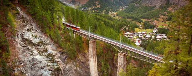 Zermatt, Switzerland. Gornergrat red tourist train on the bridge in Swiss Alps banner panorama