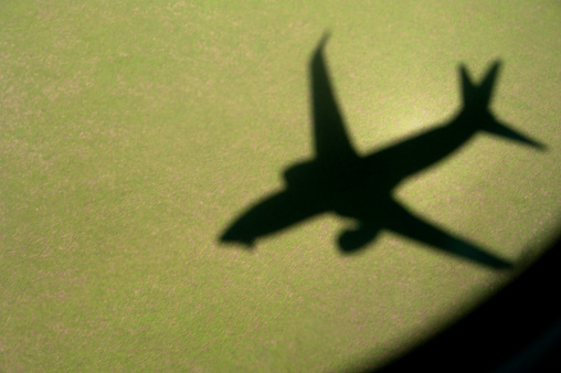 The shadow of an airplane approaching the ground is on a smooth ground.