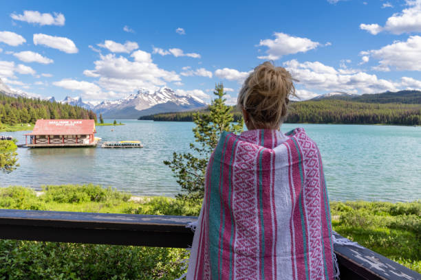 donna bionda tiene in mano una coperta rosa mentre si gode la vista del lago maligne nel jasper national park alberta canada - lago maligne foto e immagini stock