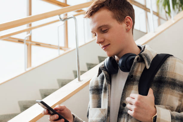 istock University student looking at his smartphone while standing at staircase 1413672289