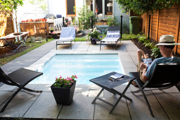A man reading in his back yard by the pool stock photo