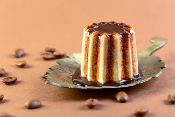 A beautifully presented chocolate panna cotta served in a glass cup with a creamy layered base. Decorated with whipped cream, a bright cherry and white chocolate accents, and plated on a white dish over a yellow tablecloth. Ideal for pastry arts, restaurant menus, culinary promotions and gourmet dessert themes.