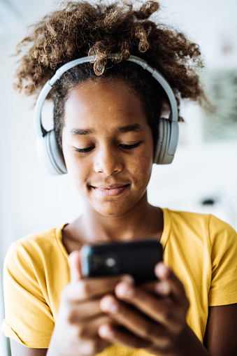 African American girl relaxing on mobile phone or laptop, listening to music or playing games