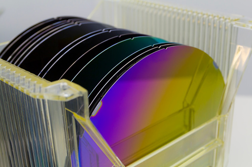 Silicon Wafers different color in plastic storage box in clear room of semiconductor foundry.