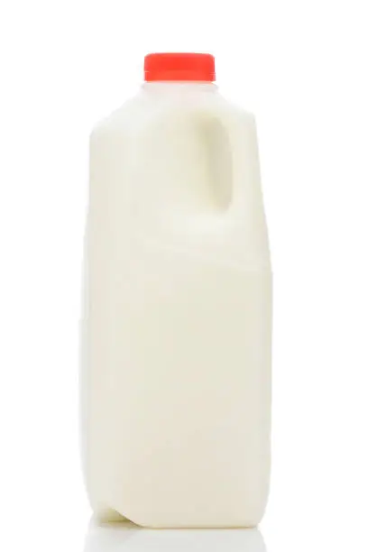 A one quart plastic bottle of milk, with red cap and no label., on white with reflection.