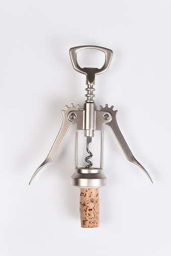 A wing style corkscrew and cork on white, overhead shot closeup.