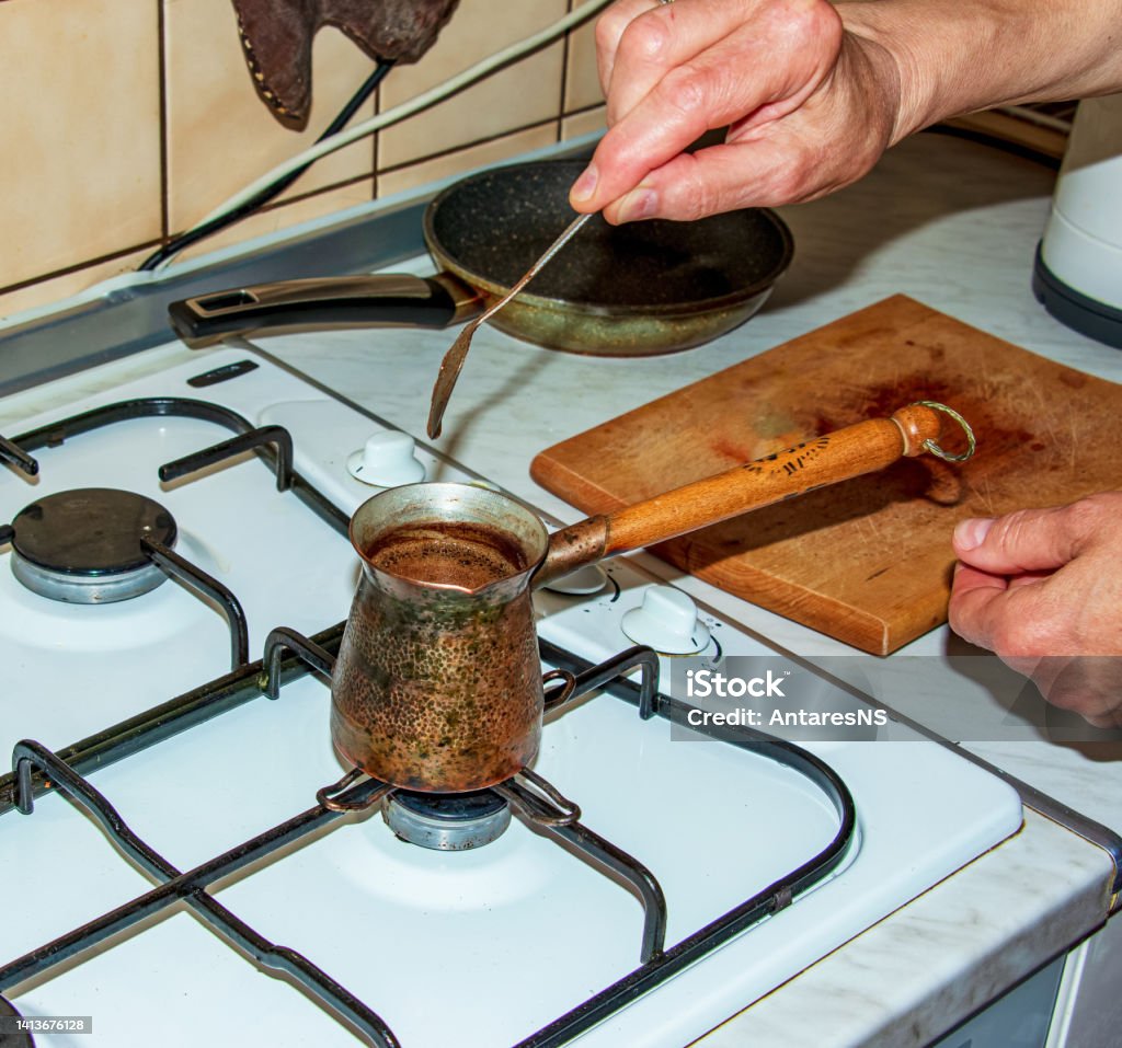 Ground coffee is brewed in a copper cezve on a gas stove. Boiling Stock Photo