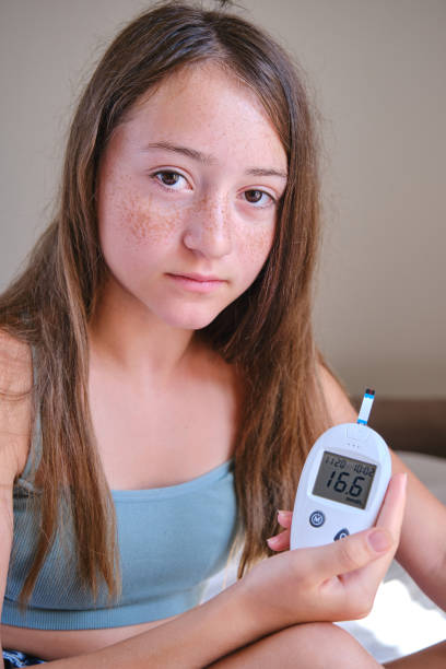 10代の少女がグルコメーターの画面を見せ、糖尿病の血液検査の結果をカメラに映し出す。 - hypoglycemia diabetes child hyperglycemia ストックフォトと画像
