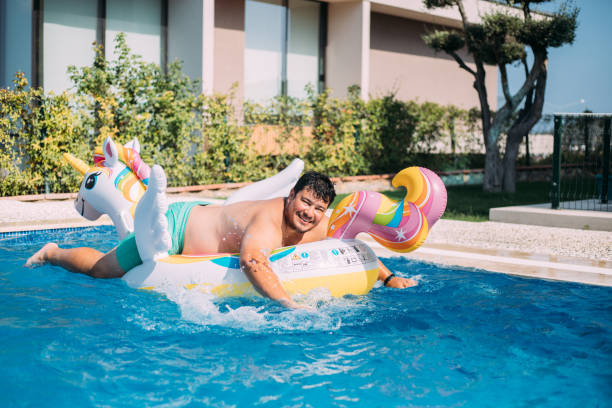 istock Man on inflatable unicorn float in swimming pool 1413678808