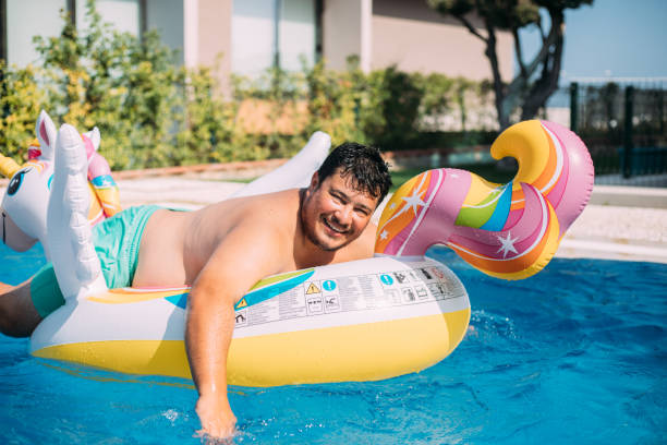 istock Man on inflatable unicorn float in swimming pool 1413678850