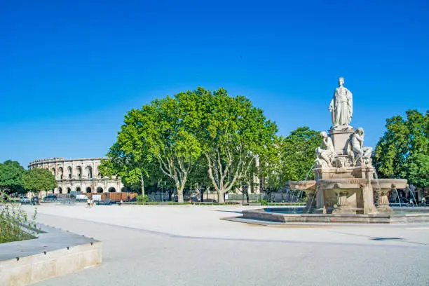Nimes, city in Southern France, Gard, Occitanie, Pradier fountain and Arena of Nîmes, Roman amphitheatre on summer day