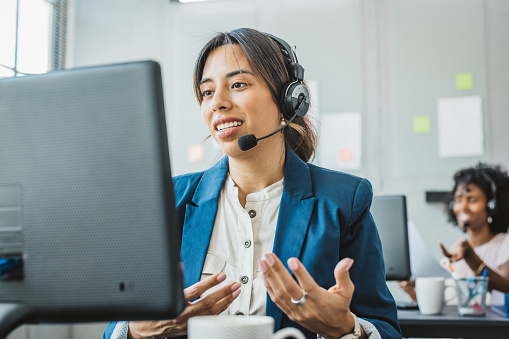 Friendly woman in call center service talking with costumers by headset. Call center and diverse people group in business.