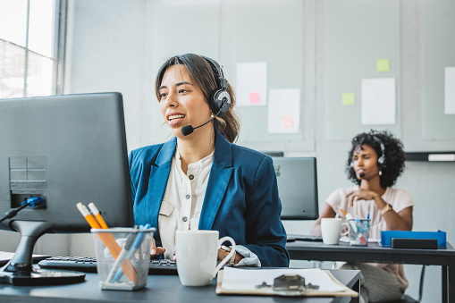 Friendly woman in call center service talking with costumers by headset. Call center and diverse people group in business.