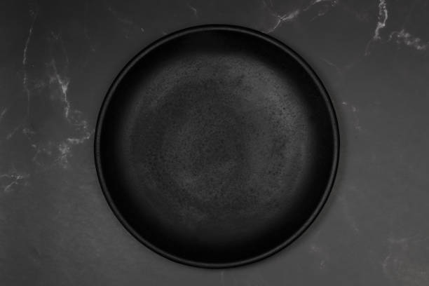 istock Black round dish on a black marble kitchen counter 1413684656