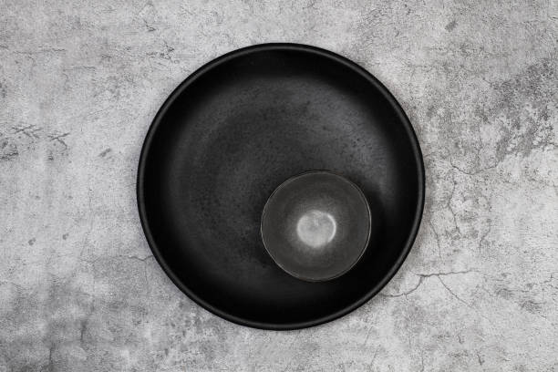 istock Black round dish and a dark bowl on a stone background 1413684661