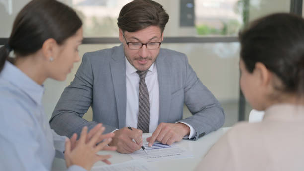 istock Middle Aged Businessman Discussing Papers with Female Colleagues 1413684833