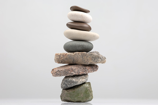 pyramid of stacked stones on a light background. stabilization and balance in life