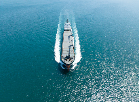 Aerial view Top speed with beautiful wave of container ship full load container with crane loading container for logistics import export or transportation concept background.