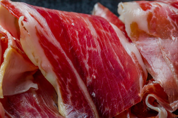 испанский хамон (hamon), па�рмская ветчина, нарезанная на тарелке экстремальным макро крупным планом - ham kitchen knife meat iberian стоковые фото и изображения