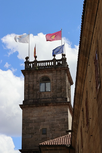 Santiago de Compostela, A Coruña, Spain. 22 May 2021. Tower of the Pazo de Fonseca with its flags, building that houses the library of the University of Santiago de Compostela. Vertical image.