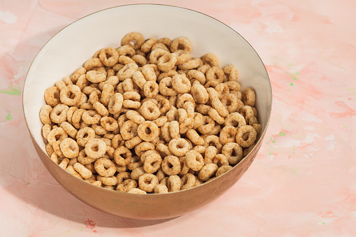Delicious honey cheerios cereal in a bowl on pink background. Close-up, flat lay, copy space. Breakfast concept