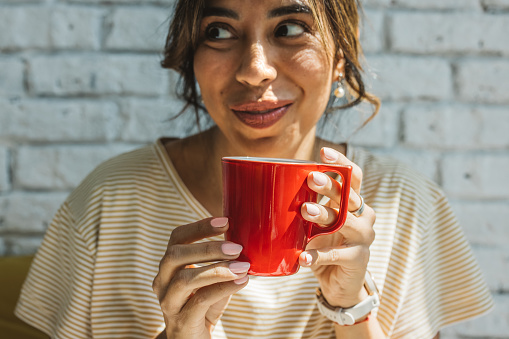 Close up of young woman holding red coffee cup.