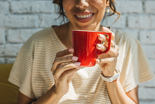 Close up of young woman holding red coffee cup.