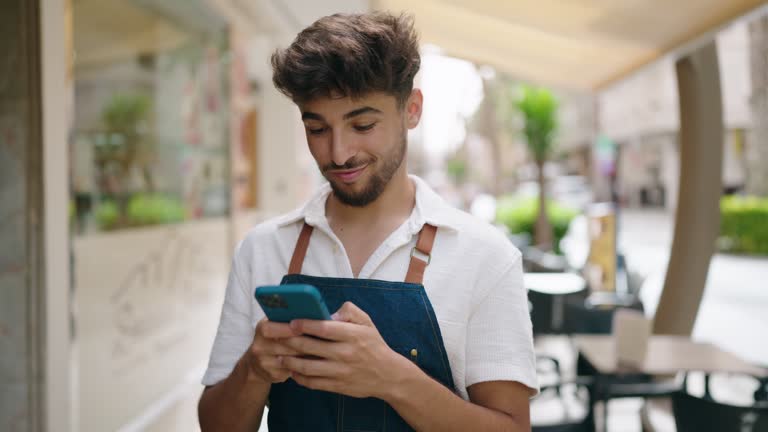 Young arab man waiter using smartphone working at restaurant