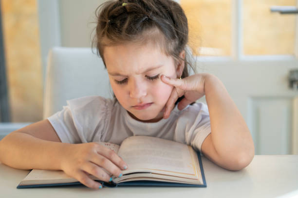 istock Girl trying to read a book with visual impairment possible myopic 1413700699