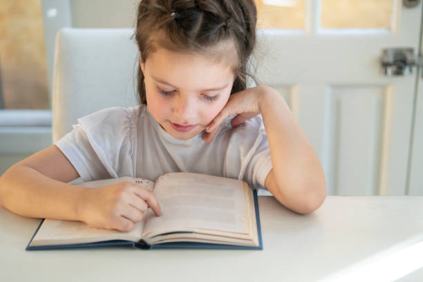 istock Girl trying to read a book with visual impairment possibly myopic 1413700703