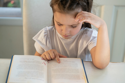 Girl trying to read a book with visual impairment possibly myopic