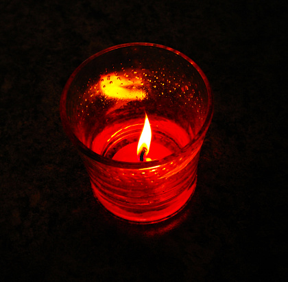 Christmas candle and festive décor on a dark background. Holiday concept for Christmas and New Year. Christmas decoration with a burning candle on the table. Selective focus.